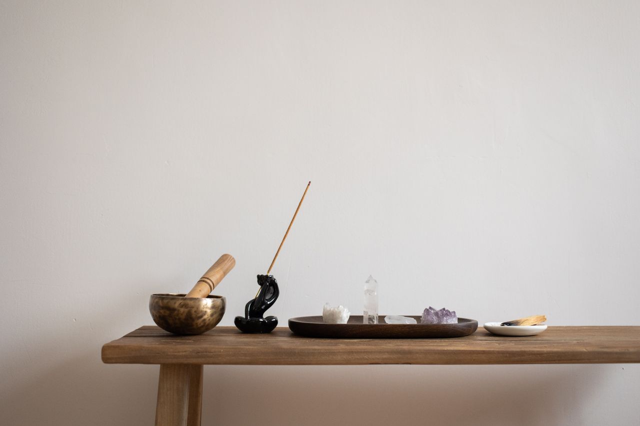 our-stories A serene setup featuring crystals, incense, and a singing bowl on a wooden table, perfect for meditation.